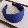Detailed shot of dark blue denim headband with yellow stitching on linen display - Dark Blue Denim