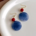 Close-up van retro gouden oorbellen met rode kralen en blauw gemarmerde hars schijven - Ronde Oorbellen (27259C) / Rood Blauw