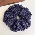 Detail eines dunkelblauen Chiffon-Haargummis mit Paisleymuster und Retro-Blumen - Blau