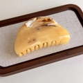 Dettaglio del fermaglio per capelli marmorizzato con trama in resina ambra e crema - Semicerchio (27268E)