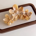 Detail view of floral tortoiseshell hair claw clip with amber resin texture on linen tray - Triple Flower (27268F)