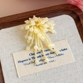 Dettaglio ravvicinato di un charm per scarpe a fiore con perline gialle su vassoio in legno - Cluster di Fiori Giallo Chiaro (27243-18)