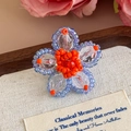 Dettaglio del ciondolo a fiore di perline fatto a mano per sabot e scarpe jelly - Fiore Cangiante Blu Con Centro Arancione (27243-21)
