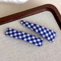 Close-up of blue and white gingham fabric hair clips set on a rustic display - Blue and White Checkered