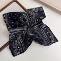 Close-up detail of a black paisley silk scarf with classic white patterns and smooth texture - Square Scarf And Hair Tie