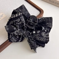Detail van een haarklem met zwart-wit Paisley-strikpatroon op linnen ondergrond - Strik Haarklem