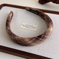 Détail d'un serre-tête écossais marron avec étiquette faite main sur textile doux - Café Plaid