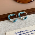 Dettaglio degli orecchini a cuore in smalto blu su superficie in tela di iuta rustica - Fibbia per Orecchio a Cuore a Spirale (27307C) / Blu Scuro e Chiaro