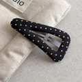 Detailed view of a black fabric BB hair clip with white polka dots on textured linen - Black Style (27299C)