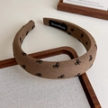 Detail eines braunen, gepolsterten Stirnbands mit Schleifenmuster und HANDMADE-Etikett - Mittelkaffee Schleife Stil (27305E)