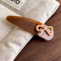 Detailed close-up of acetate bow hair clip with gold France Handmade lettering - Brown