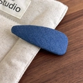 Dettaglio del fermaglio per capelli in denim blu su superficie in tela e legno naturale - Denim Blu Chiaro