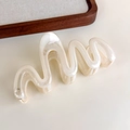 Detail of cream wavy hair claw clip with a glossy finish on a minimalist wooden tray - Transparent White Large Wave (27315Q)