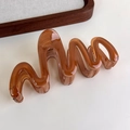 Detail of amber translucent wavy hair claw clip made of premium resin on beige background - Transparent Coffee Large Wave (27315R)