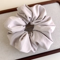 Close-up of a soft light purple fabric scrunchie with elegant pleated texture on a tray - Beige Grey