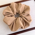 Macro shot of large khaki fabric scrunchie with rich pleats on textured base - Khaki