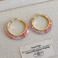 Detail of pink marble resin C-shaped hoop earrings with gold metal accents on display - Pink Acetate Style