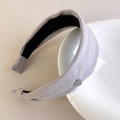 Detalle de diadema de algodón gris claro con dije de corazón sobre borde de porcelana - Gris claro