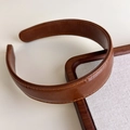 Detailed close-up of dark brown faux leather headband with premium stitching craftsmanship - Brown