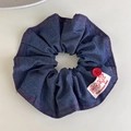 Detalle de scrunchie de mezclilla con costuras rojas, botón vintage y etiqueta tejida - Color Sólido