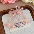 Vue détaillée du nœud en perles roses fait main avec des pompons à fleurs - Noeud Rose Tassel (27337-21)