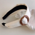 Close-up of velvet headband with acetate buckle on a decorative shell plate - Beige