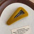 Détail d'une pince à cheveux triangulaire en velours jaune moutarde sur fond rétro - Triangulaire / Jaune