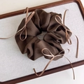 Primer plano de coletero de tela marrón con elegantes lazos de cinta en bandeja de madera - Café Oscuro