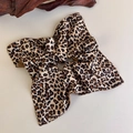 Close-up of leopard print satin scrunchie with silky texture on a beige background - Brown Black Beige Leopard Satin (27382B)