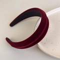 Detalle de diadema de terciopelo burdeos sobre un plato de cerámica crema con luz suave - Burdeos