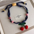 Detail of handmade crochet cherry pendant necklace with leopard print beads on linen fabric - Denim Cherry Style (27430B)