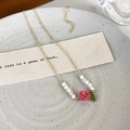 Dettaglio della collana rosa con catena dorata, perle bianche e ciondolo a foglia smaltata - Stile Rosa Rosa