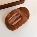 Detail einer bernsteinfarbenen großen Haarklammer aus Acetat auf einem Holztablett - Bernstein Ovaler Stil (27315H)