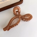 Close-up of amber butterfly hair claw clip with glossy finish and metal spring on wood decor - Amber Bowknot Style (27315M)