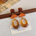 Detail van barnsteenkleurige hars oorbellen op vintage krant en linnen stof - Amber