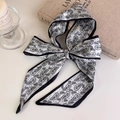 Close-up of narrow paisley silk scarf tied in a bow with elegant grey and black details - Black and White Paisley