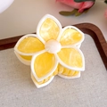 Detail view of yellow floral hair claw clip with marble texture in a wooden tray - Multicolor Gradient