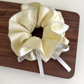 Dettaglio dello scrunchie oro champagne con bordo argento e nastri di raso bianco - Stile Giallo