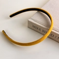 Detalle de una fina diadema de terciopelo amarillo mostaza sobre un libro con luz suave - Amarillo