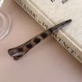 Nahaufnahme einer Haarspange mit Leopardenmuster auf einem Vintage-Buch-Hintergrund - Schmales Graues Leopardenmuster (27456A)