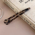 Detail einer Acetat-Haarklammer mit Leopardenmuster auf einem Vintage-Buch - Hohles Graues Leopardenmuster (27456C)