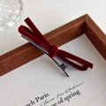 Close-up of a burgundy velvet bow hair clip on a vintage aesthetic display tray - Red