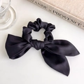 Dettaglio dell'elastico in raso nero con fiocco lungo su uno sfondo chic francese - Nero