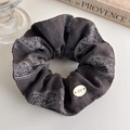 Dettaglio dell'elastico scrunchie in tessuto paisley con bottone decorativo logo - grigio scuro
