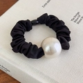 Primer plano de un coletero de seda negra con una gran perla crema sobre un libro - Cuerda Negra con Perla Blanco Crema