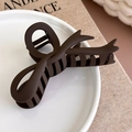 Macro-opname van een matte chocoladebruine haarklem met een stijlvol gekruist ontwerp - Donker Koffie