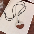 Dettaglio della collana lunga con ciondolo in metallo martellato argento e legno scuro - Base Argento Legno Caffè
