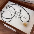 Dettaglio del ciondolo a pigna dorata su collana a cordoncino nero regolabile - Stile Oro (27507A)