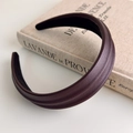 Detailed view of mocha brown faux leather headband with textured finish on a book - Fuschia