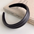 Detailed view of black faux leather headband with litchi texture on vintage book background - Black